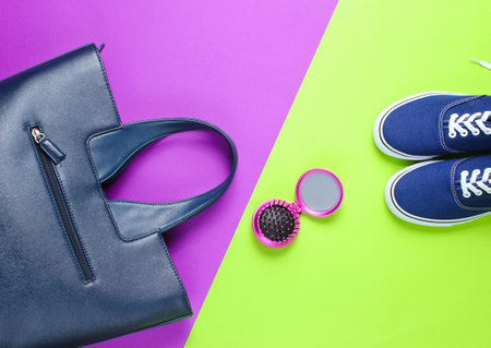 Women's accessories. Leather bag, sneakers, comb-mirror on two-color paper background. Top viewの写真素材