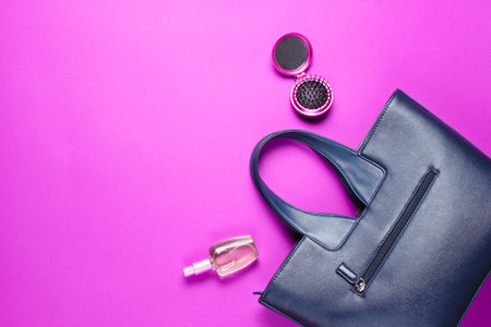 Women's accessories. Leather bag, perfume bottle, comb-mirror on pink paper background. Top view. Copy spaceの写真素材
