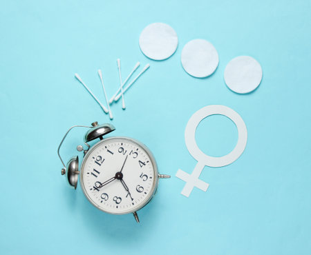 Self care time. Products for hygiene, female gender symbol, retro alarm clock on blue pastel background. Top view. Flat layの写真素材