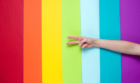 LGBT concept. Minority sex. Hand showing peace sign on rainbow background. Top view, minimalismの写真素材