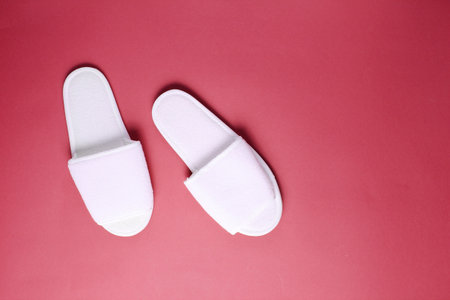 White hotel slippers on red background. Top view. Minimalism