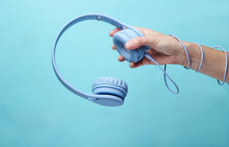 Hand wrapped cable holds headphones on blue backgroundの写真素材