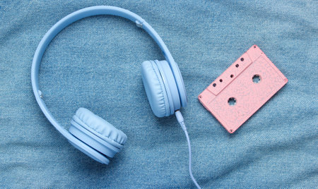 Pop culture attributes eighties. Headphones, audio cassette on denim background. Top viewの写真素材