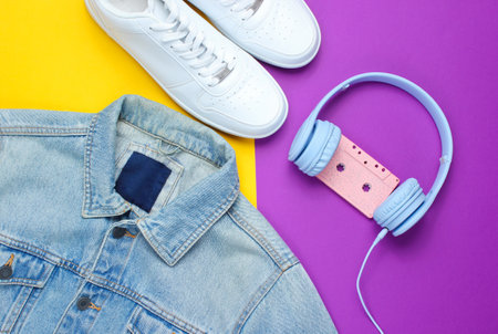 Retro style. 80s. Pop culture. Minimalism. Denim jacket, headphones with audio cassette, white sneakers against purple-yellow background. Top viewの写真素材