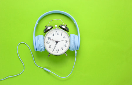 Retro alarm clock with wired headphones on green background. Top viewの写真素材