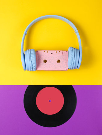 Minimalism. Headphones with audio cassette, lp record on purple-yellow background. Retro 80s. Music lover. Creative Flat lay. Top view.の写真素材