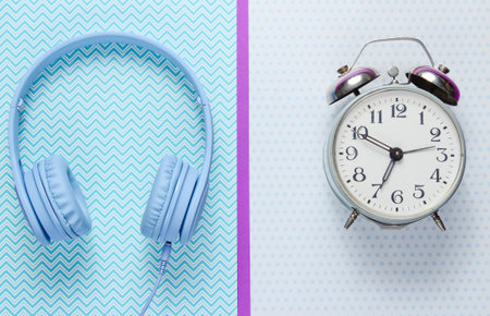 Music time concept. Retro alarm clock and headphones on creative background. Top viewの写真素材