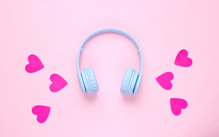 Blue headphones and hearts on pink background. Romantic music concept. Flat lay, top view, minimalismの写真素材