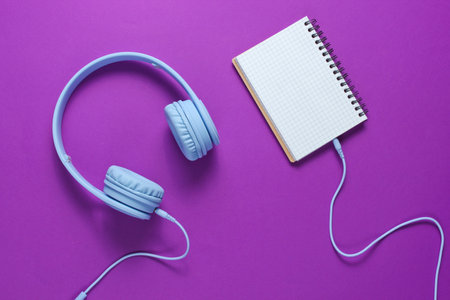 Headphones with a black background on purple background, minimalism. Flat lay. Top view.の写真素材