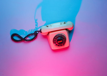 Vintage rotary phone. Retro wave, pink blue neon light, ultraviolet. Top view, minimalismの写真素材