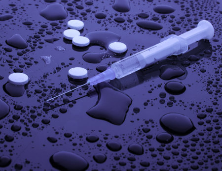 Drug concept, addiction. Syringe and pills on dark background with water drops. Night life. Purple lightの写真素材
