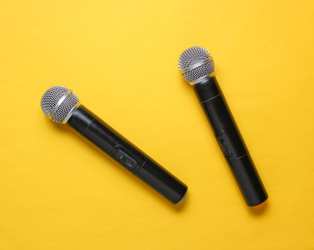 Two wireless microphone on yellow background. Flat lay.  Top view