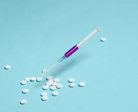 Medical minimalistic concept. Syringe, pills on blue background.