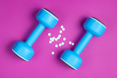 Sports Pharmacy. Plastic dumbbells, pills on purple background. Top view.の写真素材