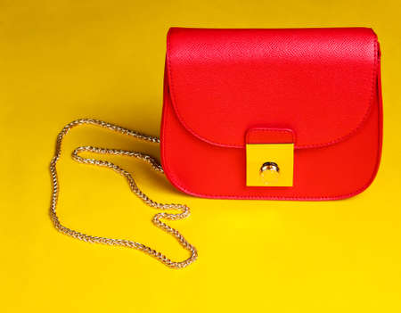 Red leather mini bag with chain on yellow background.の写真素材