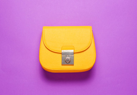 Yellow leather mini bag on purple background. Minimalism fashion concept. Top viewの写真素材