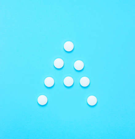 Vitamin A. Letter A from white pills on blue background. Minimalistic medical concept. Top view.の写真素材