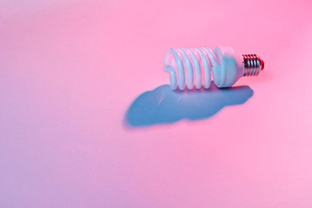 Spiral eco light bulb on neon light background. Minimalism concept