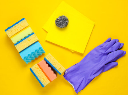 Housewife home cleaning kit on yellow background. Sponges, abrasives, rubber gloves.の写真素材
