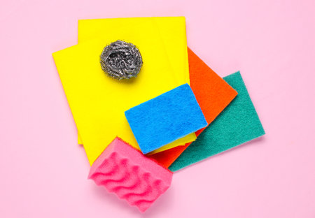 Home and bathroom cleaning kit on pink background. Sponges, abrasives.