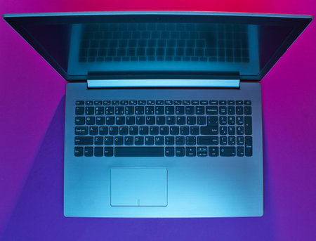 Modern laptop with vibrant gradient pink blue neon  lights. Minimalism. Top viewの写真素材