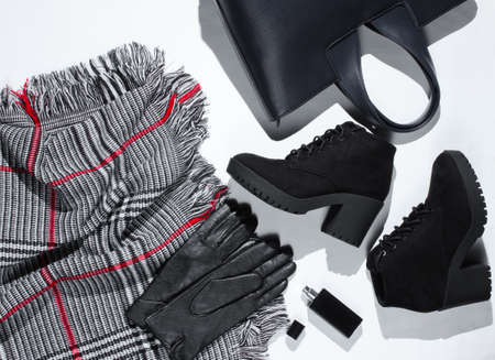 Autumn wardrobe. Women's things, shoes and accessories on a white background. Suede boots, bag, leather gloves, bottle of perfume, scarf. Flat layの写真素材