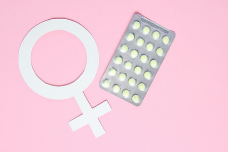 Women's medicine minimalistic concept. Pills, female gender symbol on pink background.の写真素材