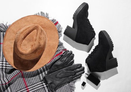 Autumn wardrobe. Women's things, shoes and accessories on a white background. Felt hat, suede boots, leather gloves, a bottle of perfume, scarf. Flat layの写真素材