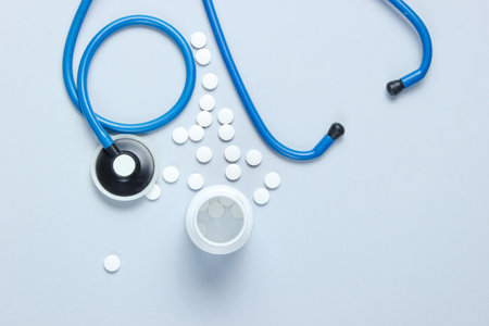 Medical creative background with a steoscope and bottle of white pills on gray background. Top viewの写真素材