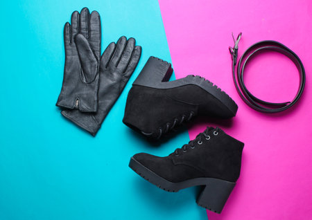 Minimalism collage of fashionable women's shoes and accessories on pink blue background. Black boots, leather gloves, belt. Top viewの写真素材