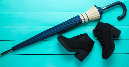 Suede black boots, umbrella on a blue wood background. Top viewの写真素材