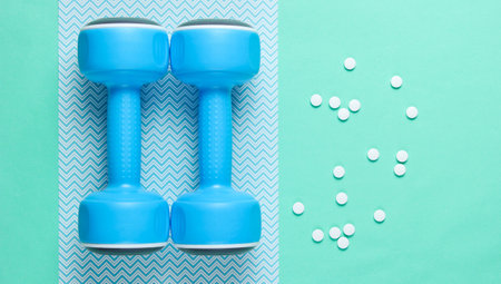 Sport concept. Dumbbells, pills on blue background. Minimalism. Top viewの写真素材