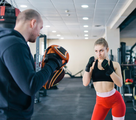 Fit blonde woman training  punch with man trainer.  at the gym. Couple exercising punching