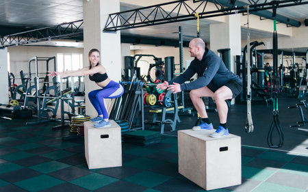 Couple functional training. Fitness man and woman jump on the wooden boxes in the gym