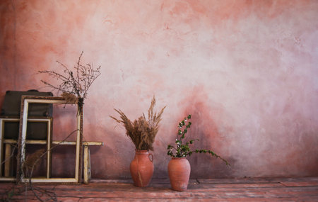 Empty frames, clay jugs with branches on the background of the wall. Vintage style interior backgroundの写真素材