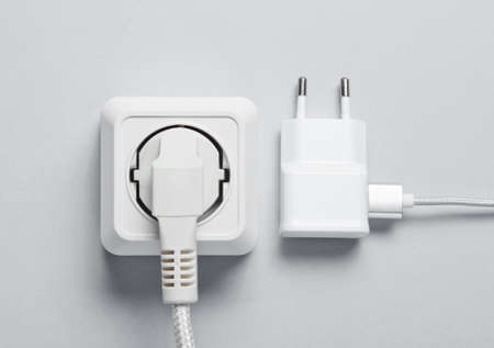 The concept of electrical dependence. The plug is plugged into the power outlet and the charger on a...