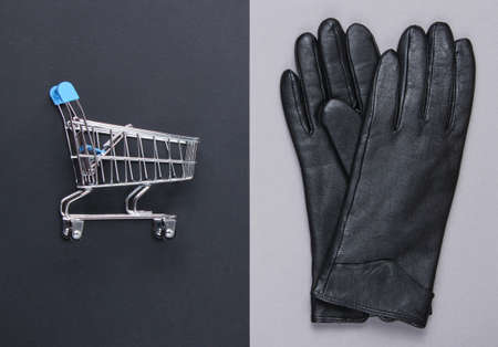Shopping concept. Mini shopping trolley, leather gloves on a gray-black background. Top viewの写真素材