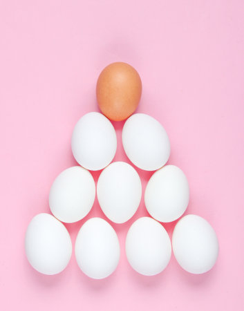 Minimalistic concept. Pyramid of eggs on pink background. The idea of uniqueness, social pyramidの写真素材