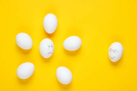 Bullying concept with eggs on yellow background. Top view, minimalismの写真素材