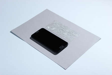 Smartphone with broken protective glass on paper background. Side viewの写真素材