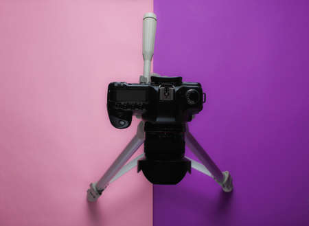 Modern digital camera with a tripod on a purple pink background. Top view. Minimalismの写真素材