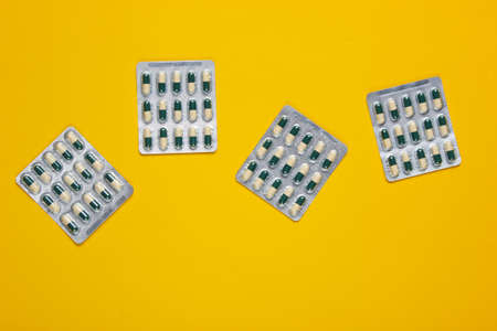 Pills blisters on yellow background. Top view.の写真素材