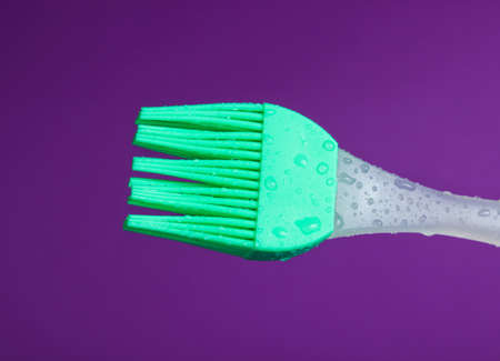 Silicone kitchen brush for cooking in drops of water on purple backgroundの写真素材