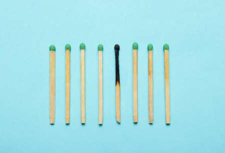 Burned and whole matches on a blue background. Minimalism conceptの写真素材