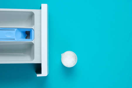 Capacity of washing machine for powder, measuring container with powder on blue background. Top view, flat layの写真素材