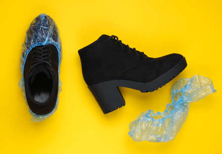Black suede boots with shoe covers on yellow background. Top  viewの写真素材