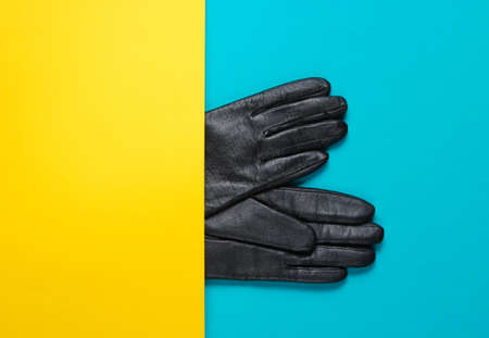 Half leather gloves on yellow-blue paper background. Minimalism creative fashion concept. Top viewの写真素材
