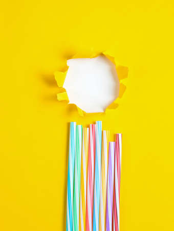 Cocktail tubes on a yellow paper background with a torn hole for copy space. Top view. Minimalism summer conceptの写真素材