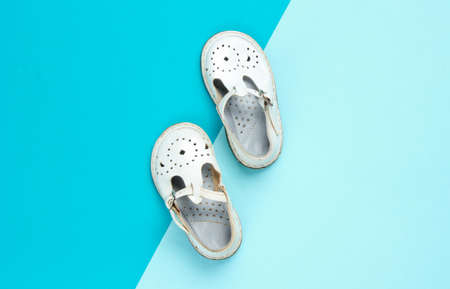 White leather children's sandals on colored pastel background. Top view