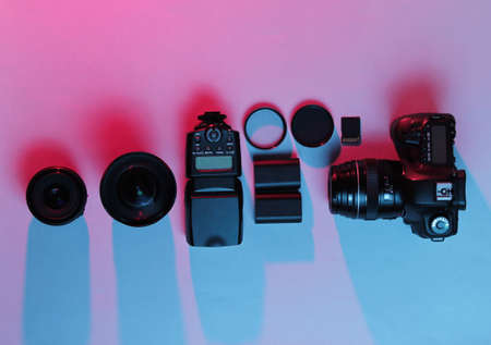Equipment professional photographer. Camera, lenses, flashes, light filters. Neon light. Top view